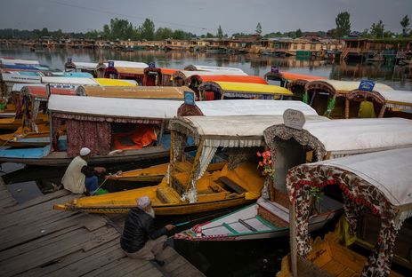 Kashmiri men catch fish as they sit next to parked 